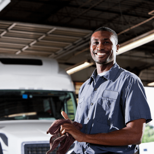 close up of mechanic smiling with truck in background